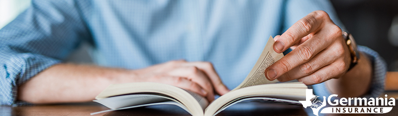 A man looking through a book of basic insurance terms