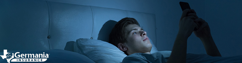 A man reading his phone in bed at night