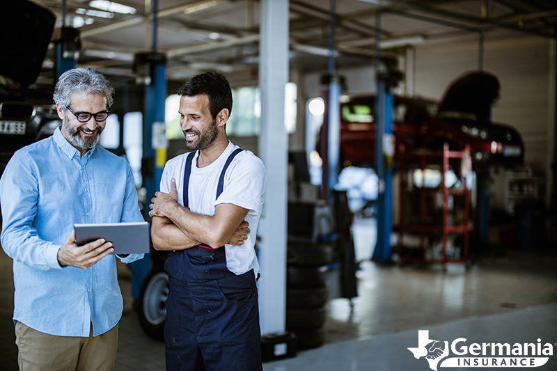 Two men in a repair shop looking at a business insurance plan on a tablet.