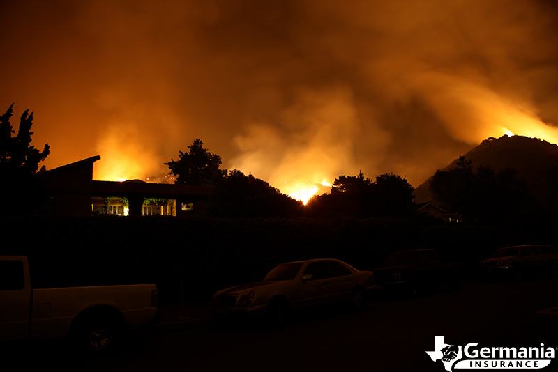 Silhouette of a house with a wildfire burning behind it