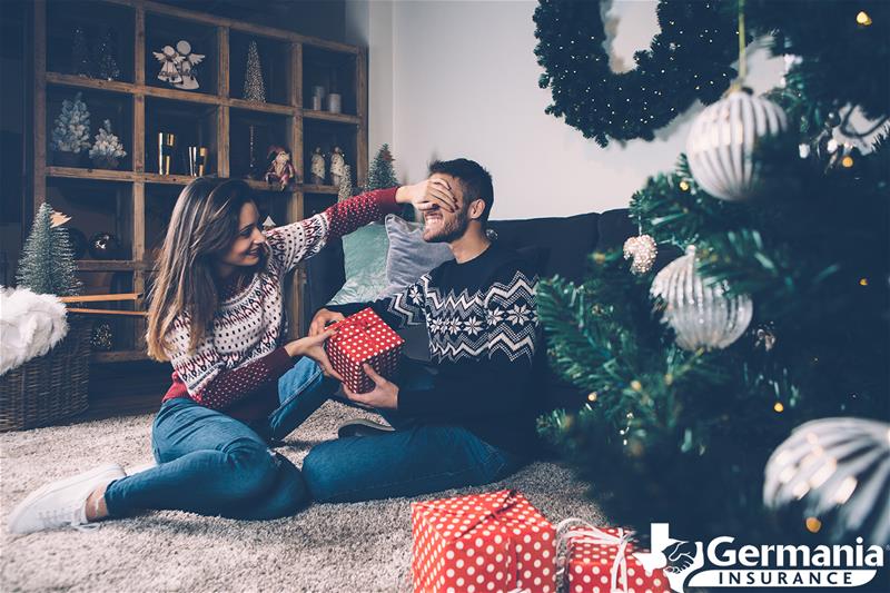 A couple opening last-minute Christmas gifts near a tree.