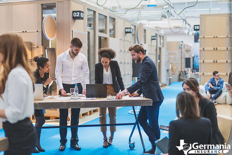 Employees working at a desk, some standing, some sitting