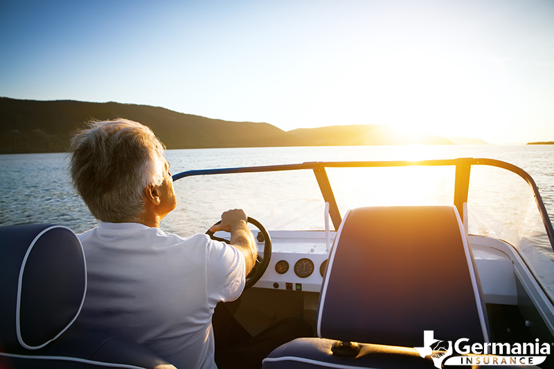 Man driving a boat on the lake, protected by boat insurance. 