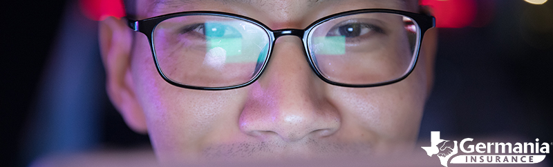 A man with glasses looking at a computer screen