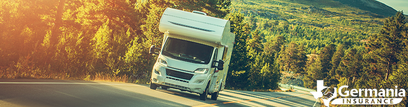 An RV driving down a tree-lined road