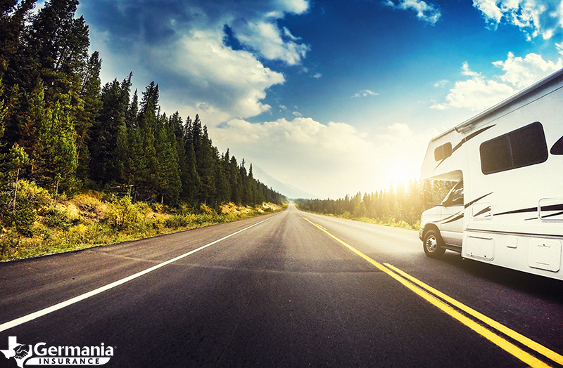 An RV driving down a tree-lined road