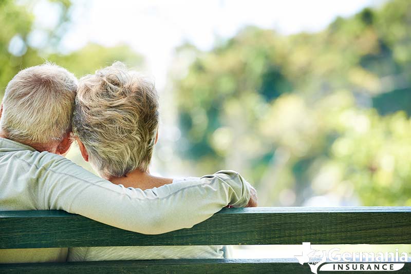 An elderly couple holding each other on a bench